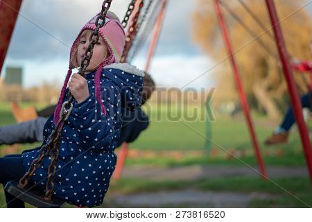 Pre-school Aged Caucasian Female In The Playground On The Swing