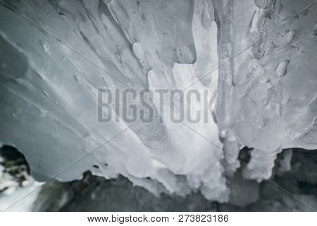 Winter Baikal. Olkhon Island. Ice Grotto. Thick Blue Ice And Icicles On The Coastal Rocks Of Olkhon 
