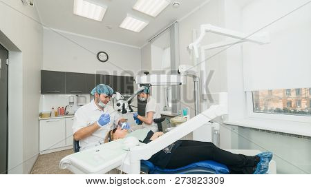 Doctor Used Microscope. Dentist Is Treating Patient In Modern Dental Office. Operation Is Carried Ou