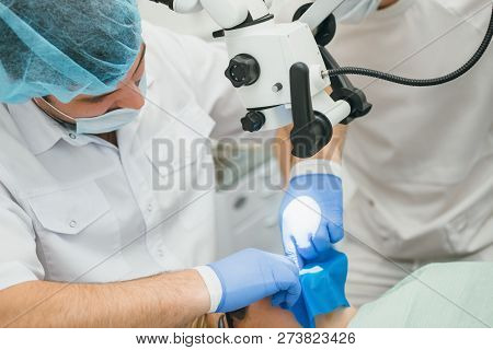 Doctor Used Microscope. Dentist Is Treating Patient In Modern Dental Office. Operation Is Carried Ou