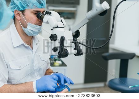 Doctor Used Microscope. Dentist Is Treating Patient In Modern Dental Office. Operation Is Carried Ou