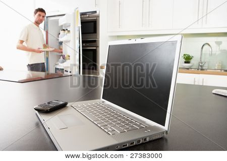 Junger Mann Befestigung Snack In Küche mit Laptop In moderne Küche
