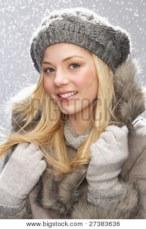 Fashionable Teenage pige iført Cap og pels i studiet med sne