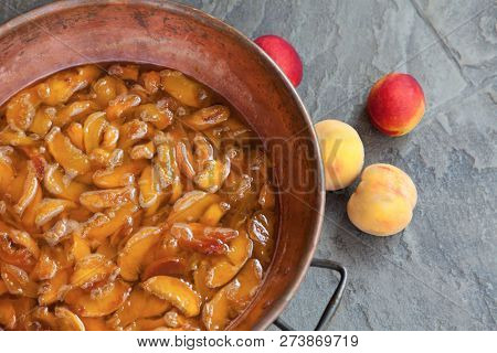 Fresh Bright Peaches And Nectarins Lay On The Stone Bricks, Close To The Copper Jar, Full Of Peach J