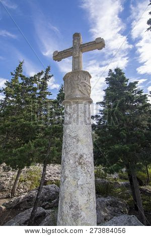 White Stone Cross Standing In Evergreen Forest