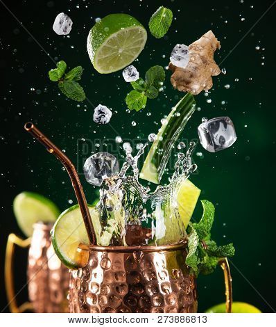 Famous splashing Moscow mule alcoholic cocktail in copper mugs, freeze motion effect.