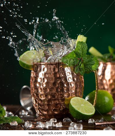 Famous splashing Moscow mule alcoholic cocktail in copper mugs, freeze motion effect.