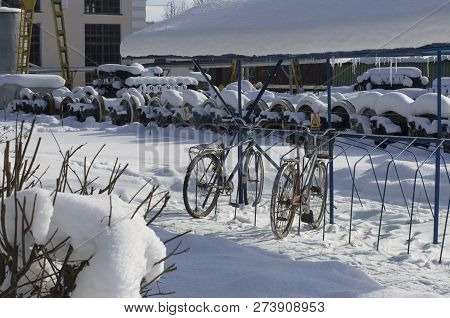 Winter Provincial Landscape With Old Parked Bicycles And A Warehouse Of Diesel Wheeled Axles Covered