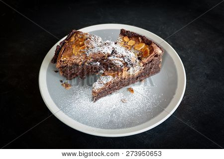 brownies cake on the table / piece of chocolate cake cocoa with nut and icing sugar on top view brownies slice on white plate the wooden table background