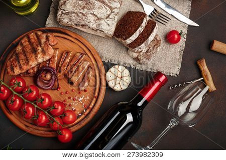 Sliced Grilled Pork Steaks With Bottle Of Wine, Wine Glass, Corkscrew, Knife, Fork, Black Bread, Che