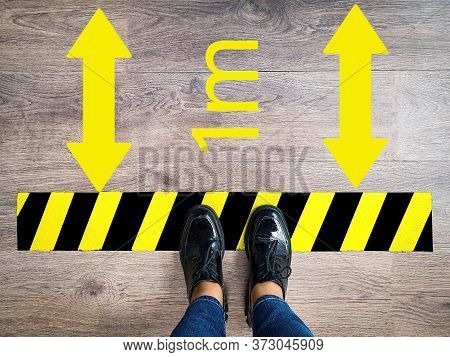 Person Stands In Line With Yellow And Black Stripes Keeping Safe Social 1m Distance, Arrow Due To Pa