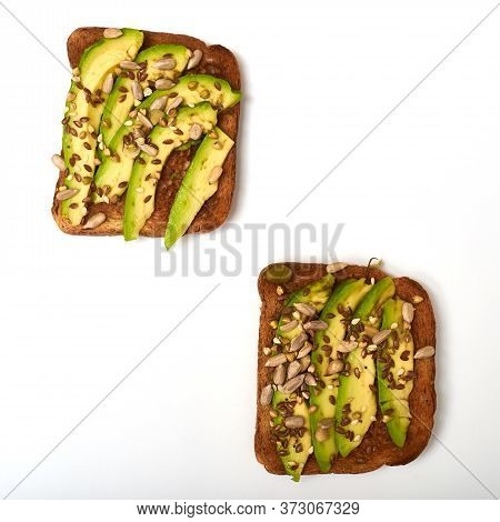 Toast With Avocado Slices, A Mixture Of Seeds On A White Background. Healthy Snack Tomorrow. The Con