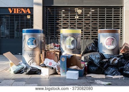 Sabadell, Spain - 06/24/2020: Trash On The Ground Around Waste Containers At Sant Roc Square