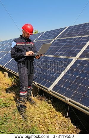 Tehnician In A Red Helmet With Laptop And The Solar Panels