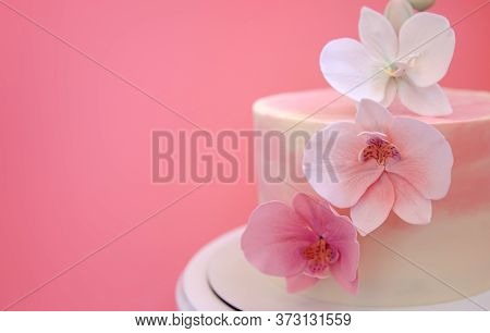 Cake Decorated With Sugar Flowers Orchids Close-up. Pink Marble Cake Stands On A Round White Stand O