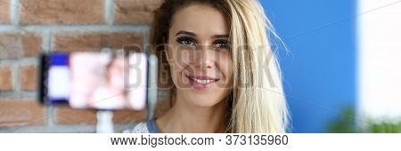 Beautiful Slim Girl Holding A Smartphone On A Selfie Stick. Young Woman Smiles In Front Of Camera On