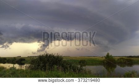 Thunderstorm Over The River. Low Clouds Before The Rain. A Thunderstorm And A Hurricane Are Approach