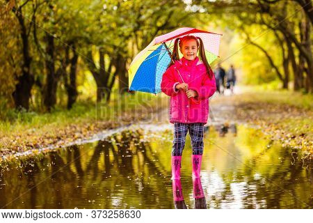 Adorable Toddler Girl With Colorful Umbrella Outdoors At Autumn Rainy Day