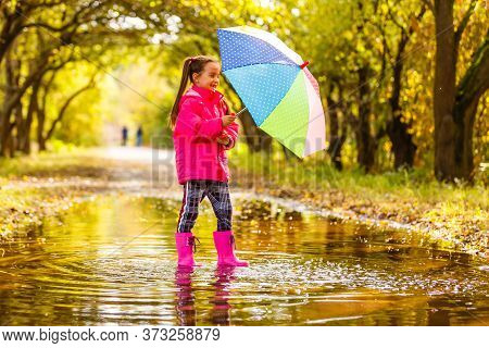 Adorable Toddler Girl With Colorful Umbrella Outdoors At Autumn Rainy Day