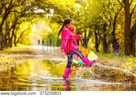 Adorable Toddler Girl With Colorful Umbrella Outdoors At Autumn Rainy Day