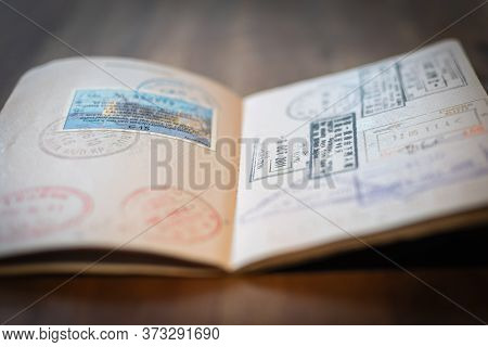 Open Passport With Different Stamps And Visas On A Wooden Surface