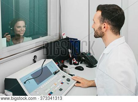 Audiologist Man Doing The Hearing Exam To An Adult Woman Patient Using An Audiometer In A Special Au
