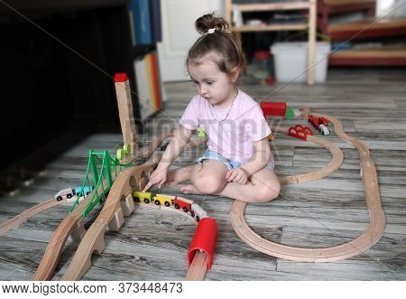 A Little Girl Is Playing A Toy Wooden Railway In The Game Room. The Concept That A Child Is Happy To