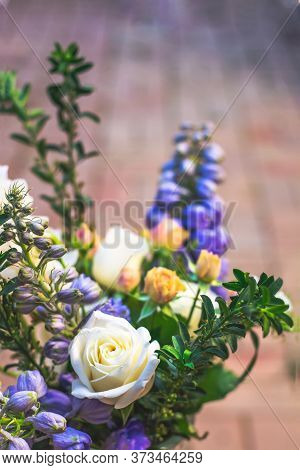 A Beautiful Bouquet With White Roses, Blue Delphiniums, And Greenary Against Neutural Background