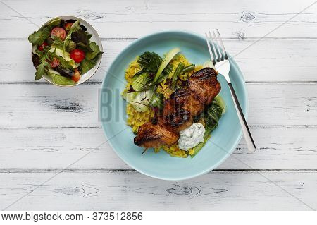 A Delicious Bowl Of  Tandoori Chicken, Vegetables And Rice, In A Light Blue Bowl Shot On A Rustic Wh