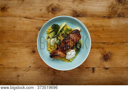 A Delicious Bowl Of  Tandoori Chicken, Vegetables And Rice, In A Light Blue Bowl Shot On A Rustic Wo