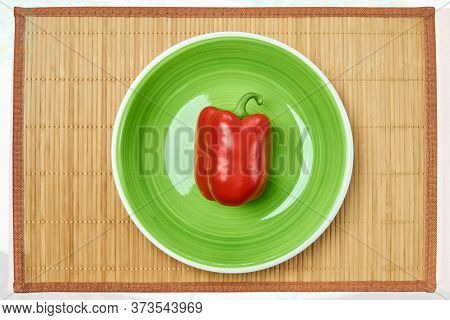 Color Still Life - Red Bell Pepper On A Green Plate On A Cane Serving Mat
