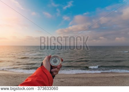 First-person View Of A Female Hand With A Compass On A Background Of A Beautiful Sea Landscape. The 