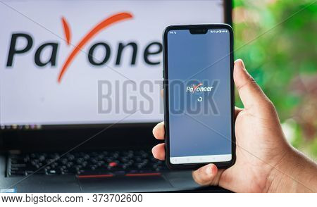 Bhairahawa, Nepal - June 27 2020: Man Uses Payoneer App On Android Phone Against The Laptop Computer