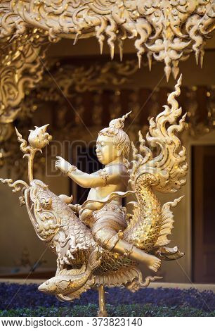 Chiang Rai, Thailand - November 15, 2019: Golden Colored Statue In Thay Style - Boy Riding A Fish Dr