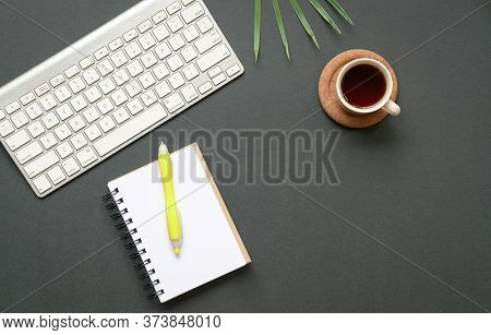 Top View Of Office Desk Or Flat Lay Of Keyboard, Coffee And Notepad With Pen. Copy Space.