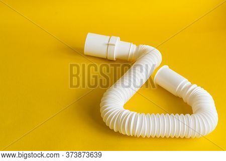 Siphon On A Yellow Background. White Plastic Siphon Sanitary For The Sink.