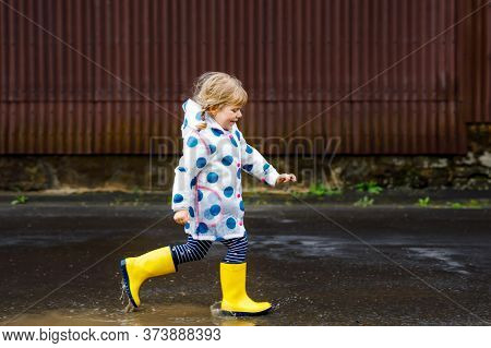 Little Toddler Girl Wearing Yellow Rain Boots, Running And Walking During Sleet On Rainy Cloudy Day.