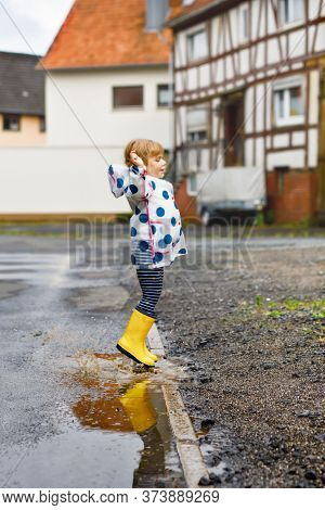 Little Toddler Girl Wearing Yellow Rain Boots, Running And Walking During Sleet On Rainy Cloudy Day.