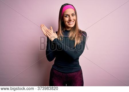 Young blonde fitness woman wearing sport workout clothes over isolated background clapping and applauding happy and joyful, smiling proud hands together