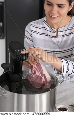 Woman Putting Vacuum Packed Meat Into Pot And Using Thermal Immersion Circulator. Sous Vide Cooking