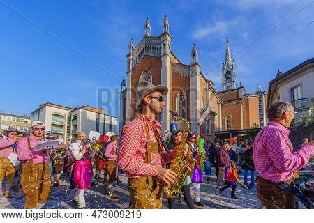Cantu, Italy - February 25, 2023: Carnival Parade, Musician Band, Crowd And The Church Of Saints Mic
