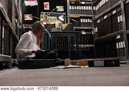 Lawyer Preparing For Case And Reading Detective Report While Sitting On Floor. African American Inve