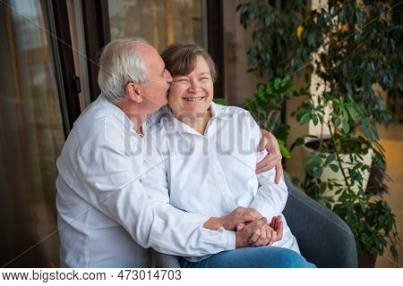 An Elderly Man Hugs And Kisses Hss Smiling Wife