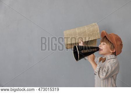 Newsboy Shouting Against Grunge Wall Background. Boy Selling Newspaper