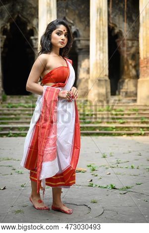 Portrait Of Beautiful Bengali Woman In Red And White Traditional Ethnic Saree And Jewellery In Front