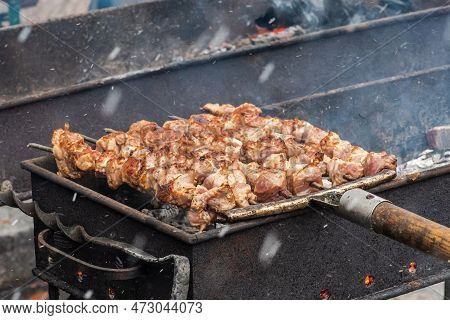Pork Meat Skewer, Grilled Or Roasted In A Barbecue With Pitchforks On An Open Fire And Flames, Shash