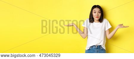 Clueless Asian Girl Shrugging Shoulders, Spread Out Hands And Looking Confused, Know Nothing, Standi