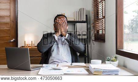 Stressed Business Man Sitting At Office Workplace. Tired And Overworked Black Man. Young African Ame