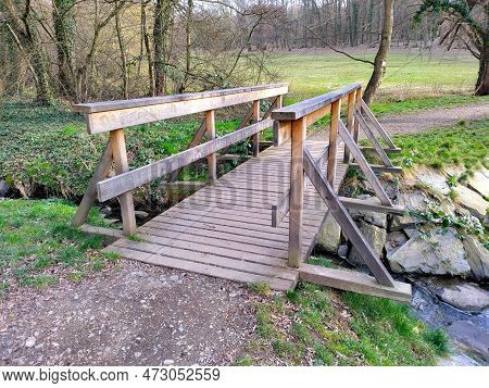 Wooden Bridge Upon A Tiny Rivulet In The Natural Park. The Bank Is Made Of Big Heavy Stones.