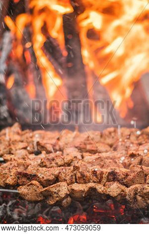 Pork Meat Skewer, Grilled Or Roasted In A Barbecue With Pitchforks On An Open Fire And Flames, Shash